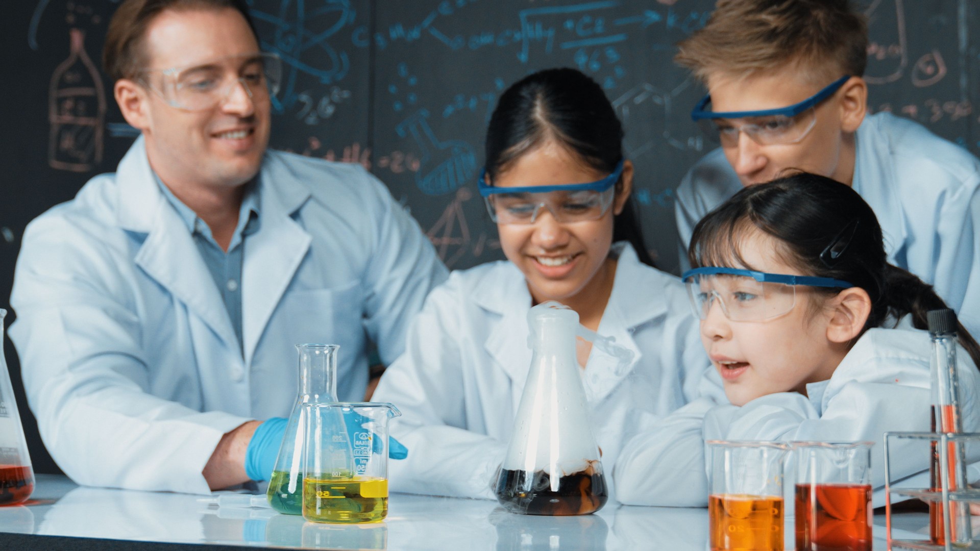 Cute girl looking at beaker while doing experiment in STEM class. Edification.