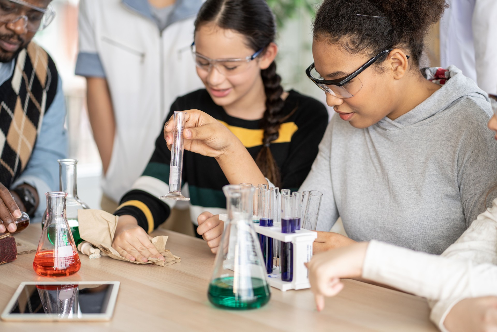 Students in science class doing chemical experiment in laboratory. Girl mixing chemistry in test tube. learning and education concept. Teacher watching and supporting kids